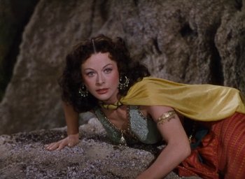 Movie still from “Samson and Delilah” (1949), directed by Cecil B. DeMille – A beautiful woman laying on the ground in a costume; Medium shot, High angle