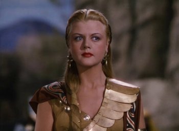 Movie still from “Samson and Delilah” (1949), directed by Cecil B. DeMille – A woman with long blonde hair wearing a gold costume; Close Up shot, Over the shoulder angle