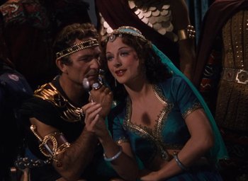 Movie still from “Samson and Delilah” (1949), directed by Cecil B. DeMille – A man and a woman sitting next to each other eating food; Medium shot, High angle