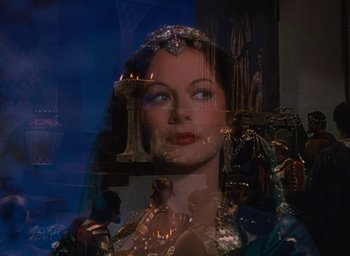Movie still from “Samson and Delilah” (1949), directed by Cecil B. DeMille – A woman with a crown is looking out of a window; Medium shot, Over the shoulder angle