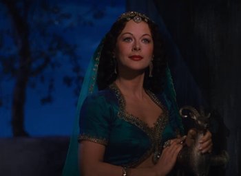 Movie still from “Samson and Delilah” (1949), directed by Cecil B. DeMille – A beautiful woman in a blue dress holding a silver object; Medium shot, Low angle