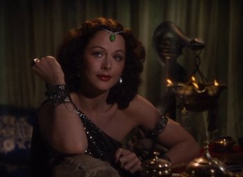 Movie still from “Samson and Delilah” (1949), directed by Cecil B. DeMille – A woman in a costume sitting in front of a statue; Medium shot, High angle