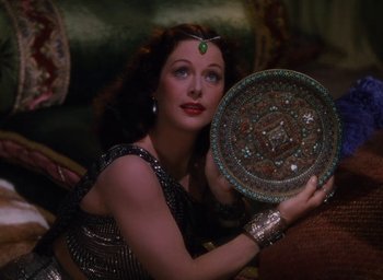 Movie still from “Samson and Delilah” (1949), directed by Cecil B. DeMille – A beautiful woman holding a plate in a dark room; Medium shot, Overhead angle