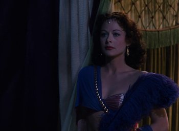 Movie still from “Samson and Delilah” (1949), directed by Cecil B. DeMille – A woman in a blue dress standing in front of a curtain; Medium shot, Over the shoulder angle