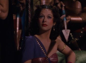 Movie still from “Samson and Delilah” (1949), directed by Cecil B. DeMille – A beautiful woman in a purple and gold dress; Medium shot, High angle