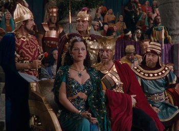 Movie still from “Samson and Delilah” (1949), directed by Cecil B. DeMille – A group of people sitting in a room with a crowd of people; Medium shot, High angle