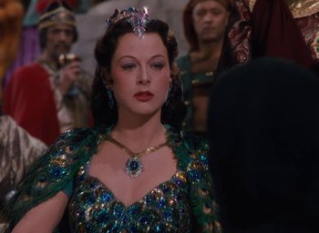 Movie still from “Samson and Delilah” (1949), directed by Cecil B. DeMille – A woman wearing a green dress and a blue tiara; Medium shot, Over the shoulder angle
