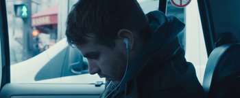 Movie still from “Simon Killer” (2012), directed by Antonio Campos – A man with headphones in his ears; Close Up shot, Over the shoulder angle