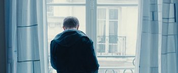 Movie still from “Simon Killer” (2012), directed by Antonio Campos – A man standing in front of an open window; Medium shot, Low angle