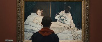 Movie still from “Simon Killer” (2012), directed by Antonio Campos – A man looking at a painting of a naked man in a bed; Medium shot, Over the shoulder angle