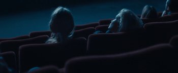 Movie still from “Simon Killer” (2012), directed by Antonio Campos – Two people sitting in a movie theater at night; Medium shot, High angle