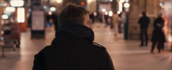 Movie still from “Simon Killer” (2012), directed by Antonio Campos – A man in a black jacket standing on a sidewalk; Close Up shot, Over the shoulder angle