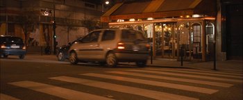Movie still from “Simon Killer” (2012), directed by Antonio Campos – A car driving down a street at night past a restaurant; Wide shot, High angle