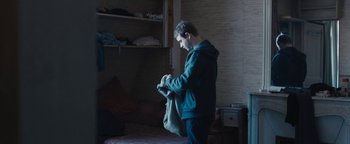 Movie still from “Simon Killer” (2012), directed by Antonio Campos – A man holding a bag in a room with shelves; Medium shot, High angle