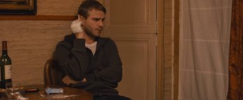 Movie still from “Simon Killer” (2012), directed by Antonio Campos – A man sitting on a chair with his hands behind his head; Close Up shot, Over the shoulder angle