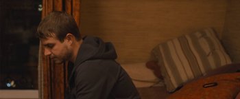 Movie still from “Simon Killer” (2012), directed by Antonio Campos – A man sitting on the ground in a room; Close Up shot, Over the shoulder angle