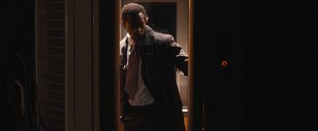 Movie still from “Simon Killer” (2012), directed by Antonio Campos – A man in a suit and tie standing next to a window; Medium shot, Over the shoulder angle