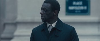 Movie still from “Simon Killer” (2012), directed by Antonio Campos – A man wearing a suit and tie standing in the rain; Close Up shot, Over the shoulder angle