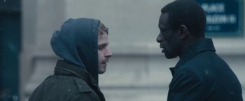 Movie still from “Simon Killer” (2012), directed by Antonio Campos – Two men standing next to each other in the rain; Close Up shot, Over the shoulder angle