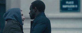 Movie still from “Simon Killer” (2012), directed by Antonio Campos – A man in black jacket talking to a person; Close Up shot, Over the shoulder angle