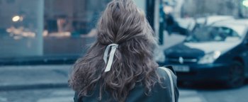 Movie still from “Simon Killer” (2012), directed by Antonio Campos – A person's hair with a bow; Close Up shot, Over the shoulder angle