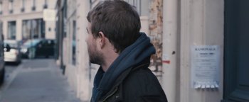 Movie still from “Simon Killer” (2012), directed by Antonio Campos – A person walking on a sidewalk; Close Up shot, Over the shoulder angle