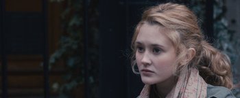 Movie still from “Simon Killer” (2012), directed by Antonio Campos – A young woman looking to her left while sitting down; Close Up shot, Over the shoulder angle