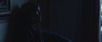 Movie still from “Simon Killer” (2012), directed by Antonio Campos – A woman sitting in a dark room with her head turned to the side; Medium shot, Low angle