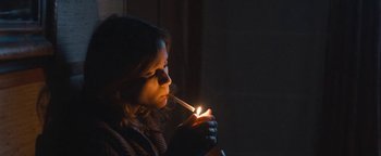 Movie still from “Simon Killer” (2012), directed by Antonio Campos – A woman is lighting a cigarette in the dark; Medium shot, Low angle