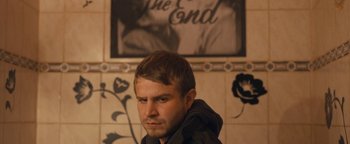 Movie still from “Simon Killer” (2012), directed by Antonio Campos – A man in a black jacket is in front of a wall; Close Up shot, Over the shoulder angle