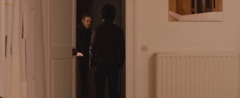 Movie still from “Simon Killer” (2012), directed by Antonio Campos – A man standing in front of a mirror in front of another man; Medium shot, Over the shoulder angle
