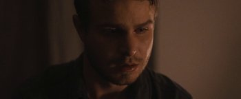 Movie still from “Simon Killer” (2012), directed by Antonio Campos – A man's face in a dark room; Close Up shot, Over the shoulder angle
