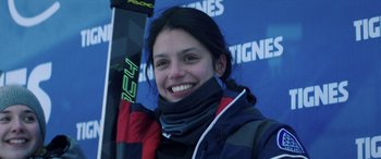 Movie still from “Slalom” (2020), directed by Charlène Favier – A woman smiles while holding a pair of skis; Close Up shot, Low angle