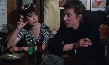 Movie still from “Smithereens” (1982), directed by Susan Seidelman – A man and a woman sitting at a table with beer; Medium shot, Over the shoulder angle