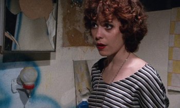 Movie still from “Smithereens” (1982), directed by Susan Seidelman – A woman with curly hair and a striped shirt; Close Up shot, Over the shoulder angle