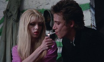Movie still from “Smithereens” (1982), directed by Susan Seidelman – A man and a woman are smoking a cigarette together; Medium shot, Low angle
