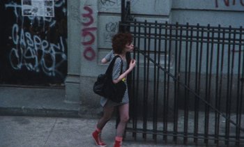 Movie still from “Smithereens” (1982), directed by Susan Seidelman – A woman walking down the street with a black bag; Wide shot, High angle