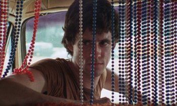 Movie still from “Smithereens” (1982), directed by Susan Seidelman – A young man is looking through a bunch of beads in a car; Close Up shot, Low angle
