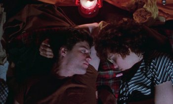 Movie still from “Smithereens” (1982), directed by Susan Seidelman – Two young men sleeping on a bed under a lamp; Medium shot, Overhead angle