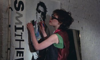 Movie still from “Smithereens” (1982), directed by Susan Seidelman – A woman painting a picture on the side of a wall; Medium shot, Over the shoulder angle