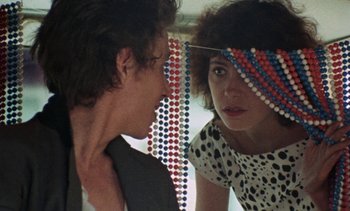 Movie still from “Smithereens” (1982), directed by Susan Seidelman – A woman looking at a man in the mirror; Close Up shot, Over the shoulder angle