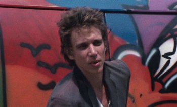 Movie still from “Smithereens” (1982), directed by Susan Seidelman – A young man standing in front of a graffiti wall; Close Up shot, Low angle