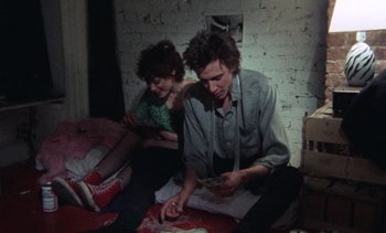 Movie still from “Smithereens” (1982), directed by Susan Seidelman – A man and a woman sitting on the floor; Medium shot, High angle
