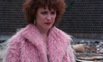 Movie still from “Smithereens” (1982), directed by Susan Seidelman – A person wearing a pink coat; Close Up shot, Over the shoulder angle