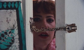 Movie still from “Smithereens” (1982), directed by Susan Seidelman – A woman with her mouth taped shut behind a door; Close Up shot, Low angle