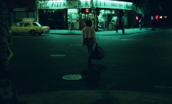 Movie still from “Smithereens” (1982), directed by Susan Seidelman – A person walking down a street at night; Extreme Wide shot, High angle