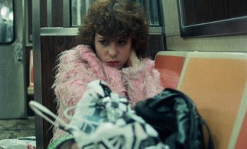 Movie still from “Smithereens” (1982), directed by Susan Seidelman – A woman sitting on a bench with her head resting on her hand; Medium shot, High angle