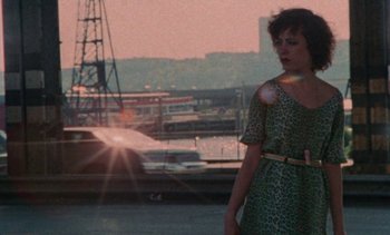Movie still from “Smithereens” (1982), directed by Susan Seidelman – A woman standing in front of a body of water; Wide shot, High angle