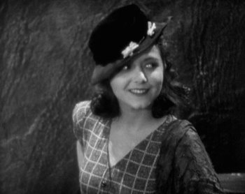 Movie still from “Street Angel” (1928), directed by Frank Borzage – A woman wearing a hat and a plaid dress; Close Up shot, High angle