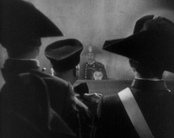 Movie still from “Street Angel” (1928), directed by Frank Borzage – A group of men standing in front of a judge; Medium shot, Over the shoulder angle